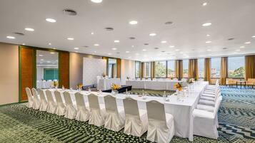 A conference room with a long table, white chairs, and a carpeted floor.