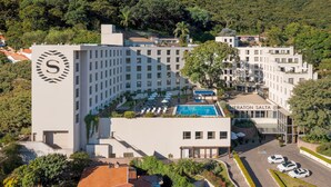 Un hotel con una piscina grande, varios pisos y un llamativo logotipo con la letra 'S'.