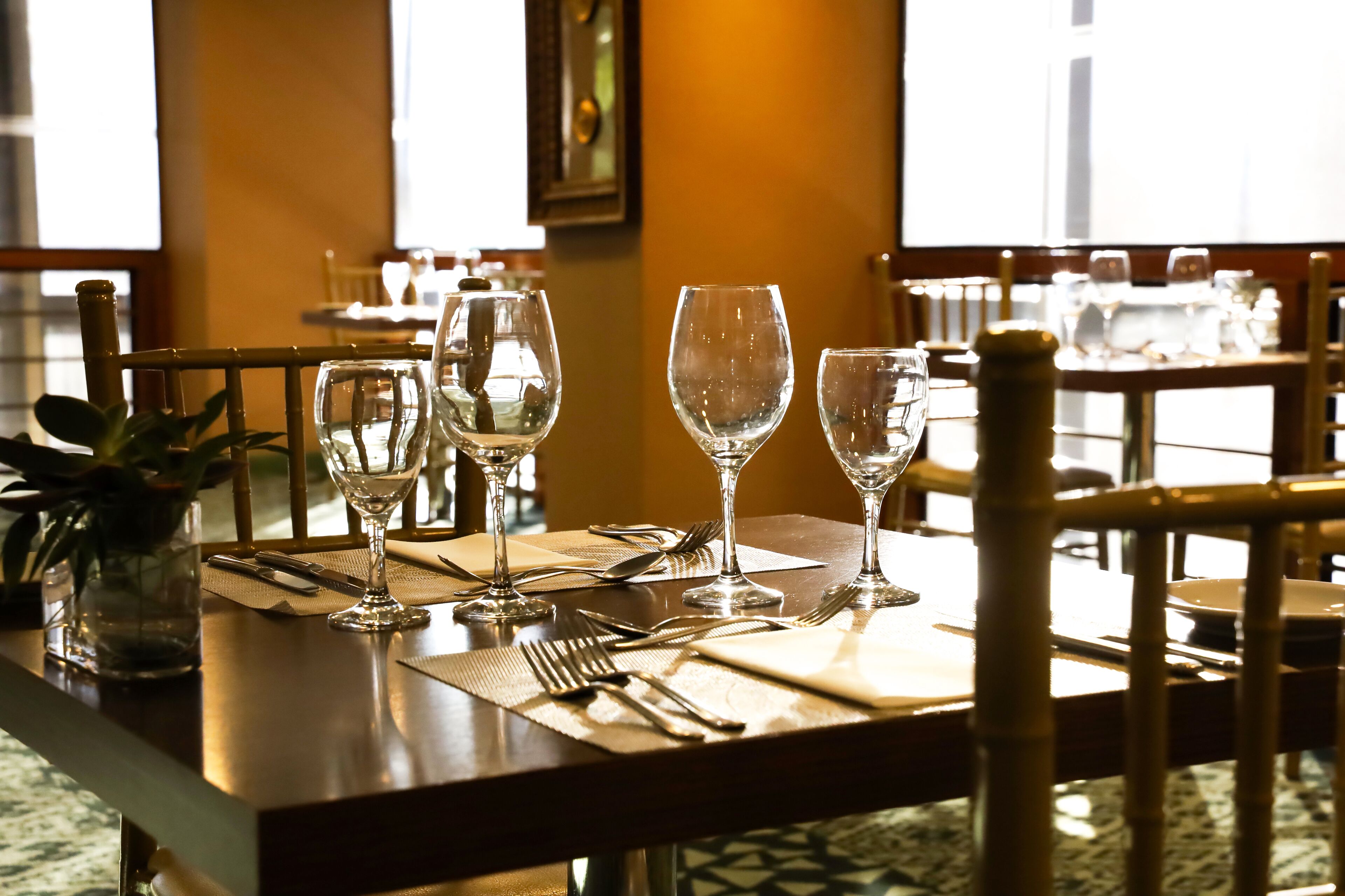 A dining table set with wine glasses, cutlery, and a vase of flowers.