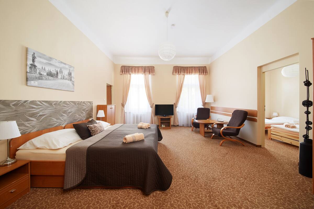 A hotel room with a large bed, a desk, a chair, a television, and a painting on the wall.