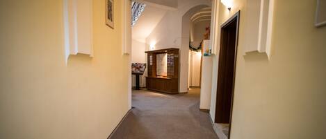A hallway with a carpeted floor, a reception desk, and a framed picture on the wall.