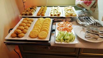 A buffet with various food items including cookies, fruit, and pastries.