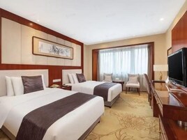 Habitación de hotel con dos camas, televisión, escritorio y una silla.
