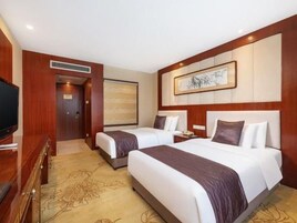 Habitación de hotel con dos camas, una televisión y una obra de arte grande en la pared.