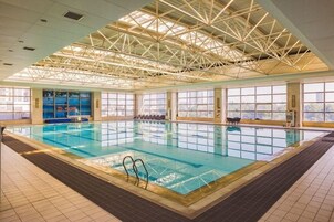 Una piscina interior con techos altos y grandes ventanales.