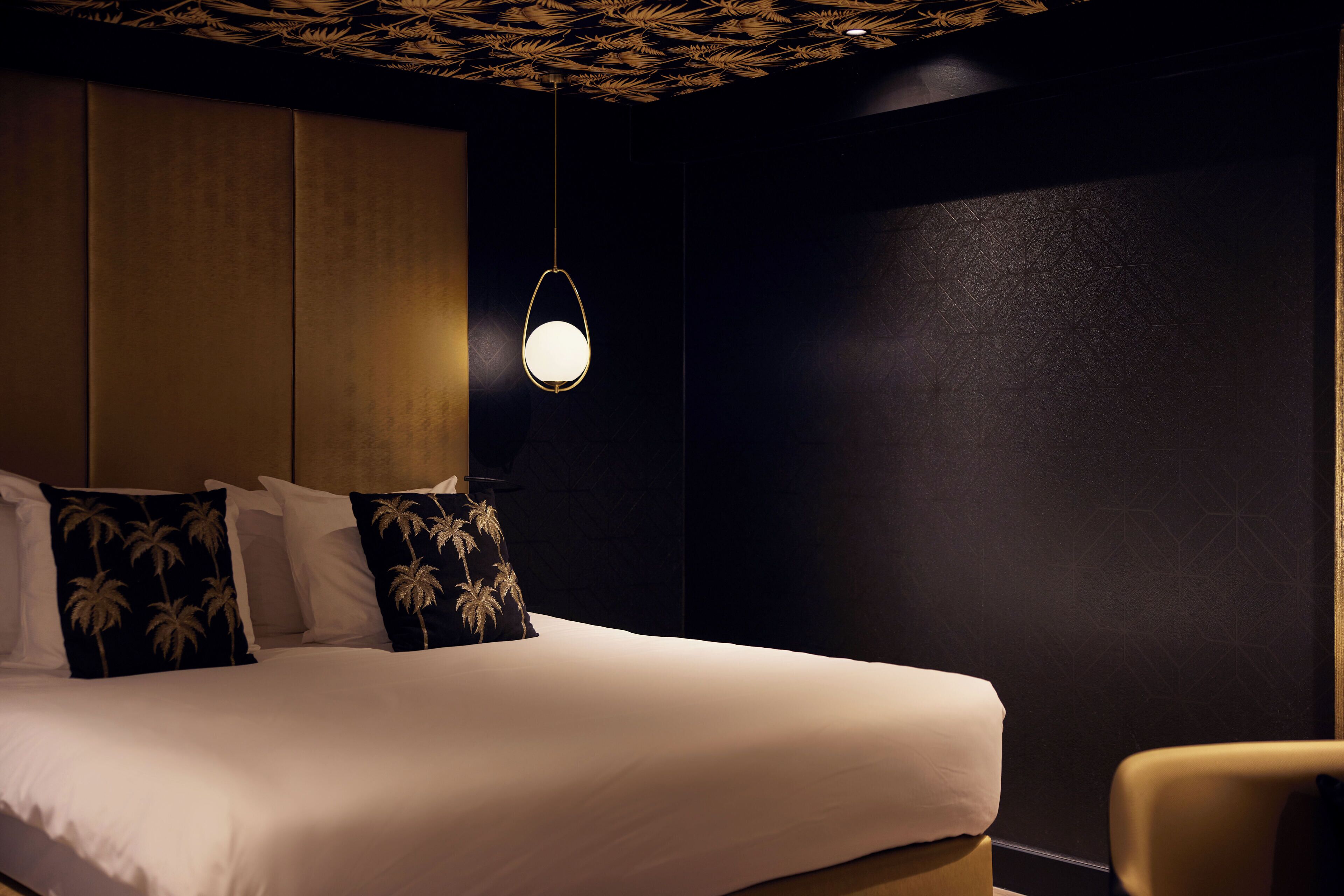 Ein Hotelzimmer mit einem großen Bett, einem Nachttisch, einem Sessel und einer Deckenleuchte.