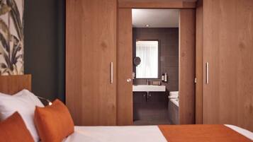 A bedroom with a bed, orange pillows, and a wooden wardrobe.