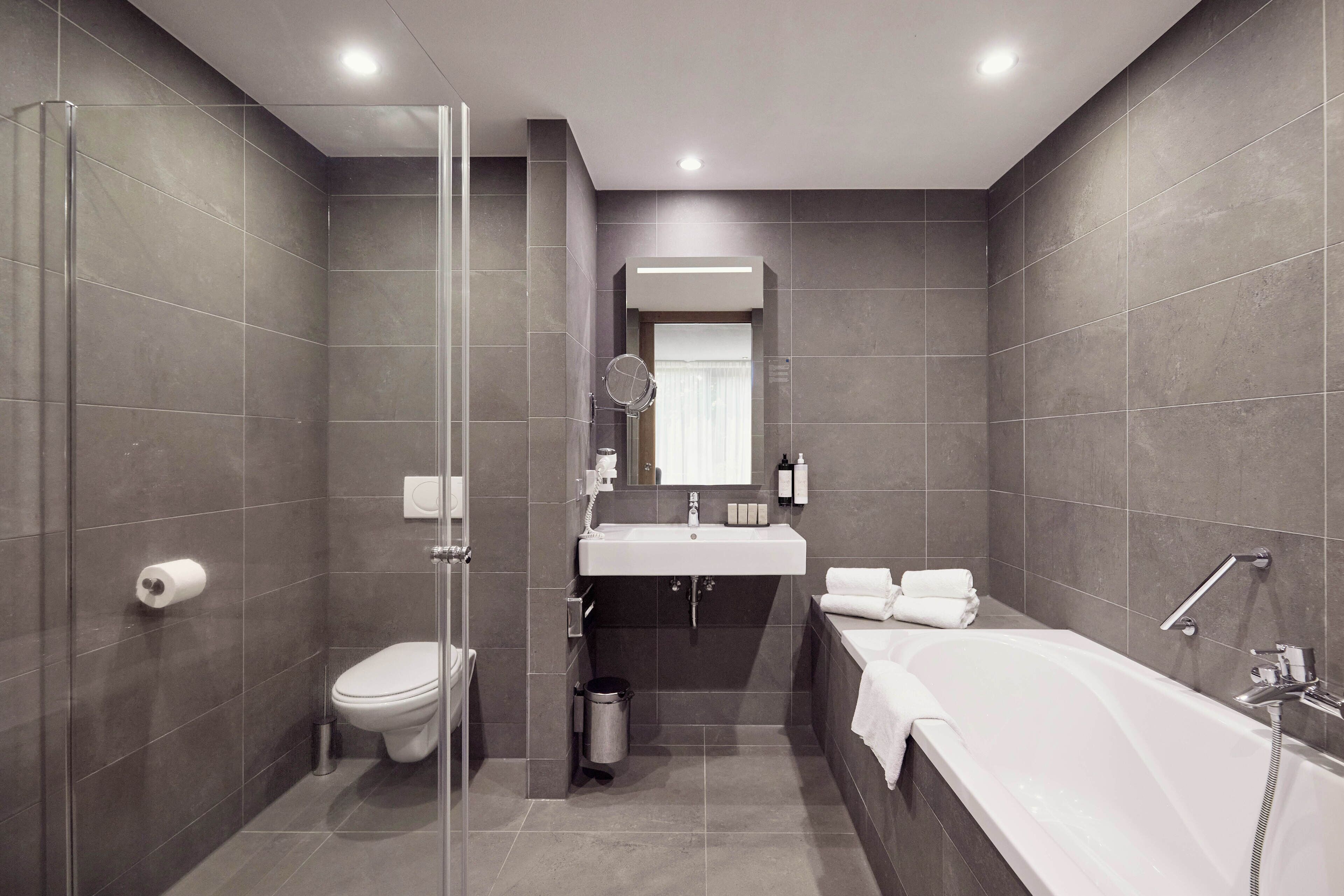 Un baño moderno con cabina de ducha de vidrio, inodoro, lavabo y bañera.