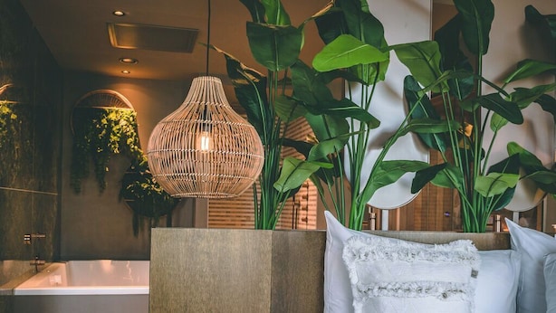 Een moderne badkamer met een vrijstaand bad, een grote spiegel en een hangende lamp.