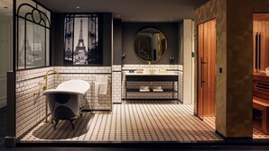 Een moderne badkamer met een vrijstaand bad, een grote spiegel en een wastafelmeubel met een wastafel.