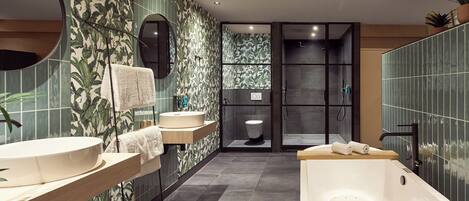 Ein modernes Badezimmer mit einer freistehenden Badewanne, zwei Waschbecken, einer Toilette und einer Duschkabine.