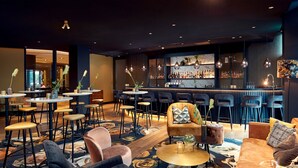 Een moderne bar met ronde tafels, barkrukken en diverse zitmogelijkheden, zoals banken en stoelen.
