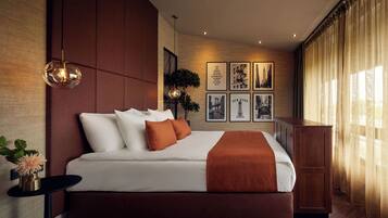 Een moderne hotelkamer met een groot bed, een nachtkastje, een wandlamp en ingelijste foto's.