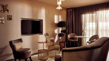 Un salon moderne doté d’un téléviseur à écran plat, d’un canapé en cuir marron, d’une table basse ronde et d’un coin repas avec une petite table et des chaises.