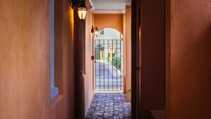 A hallway with a cobblestone floor leading to a gated entrance. - Elliott House Inn (Charleston)