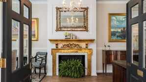 A room with a fireplace, a chandelier, and framed artwork on the walls. - Elliott House Inn (Charleston)