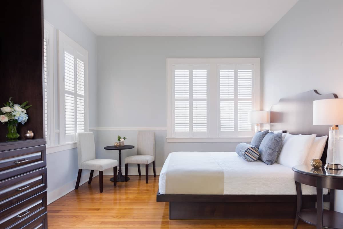 A bedroom with a bed, bedside tables, a chair, and a small table with a vase of flowers.