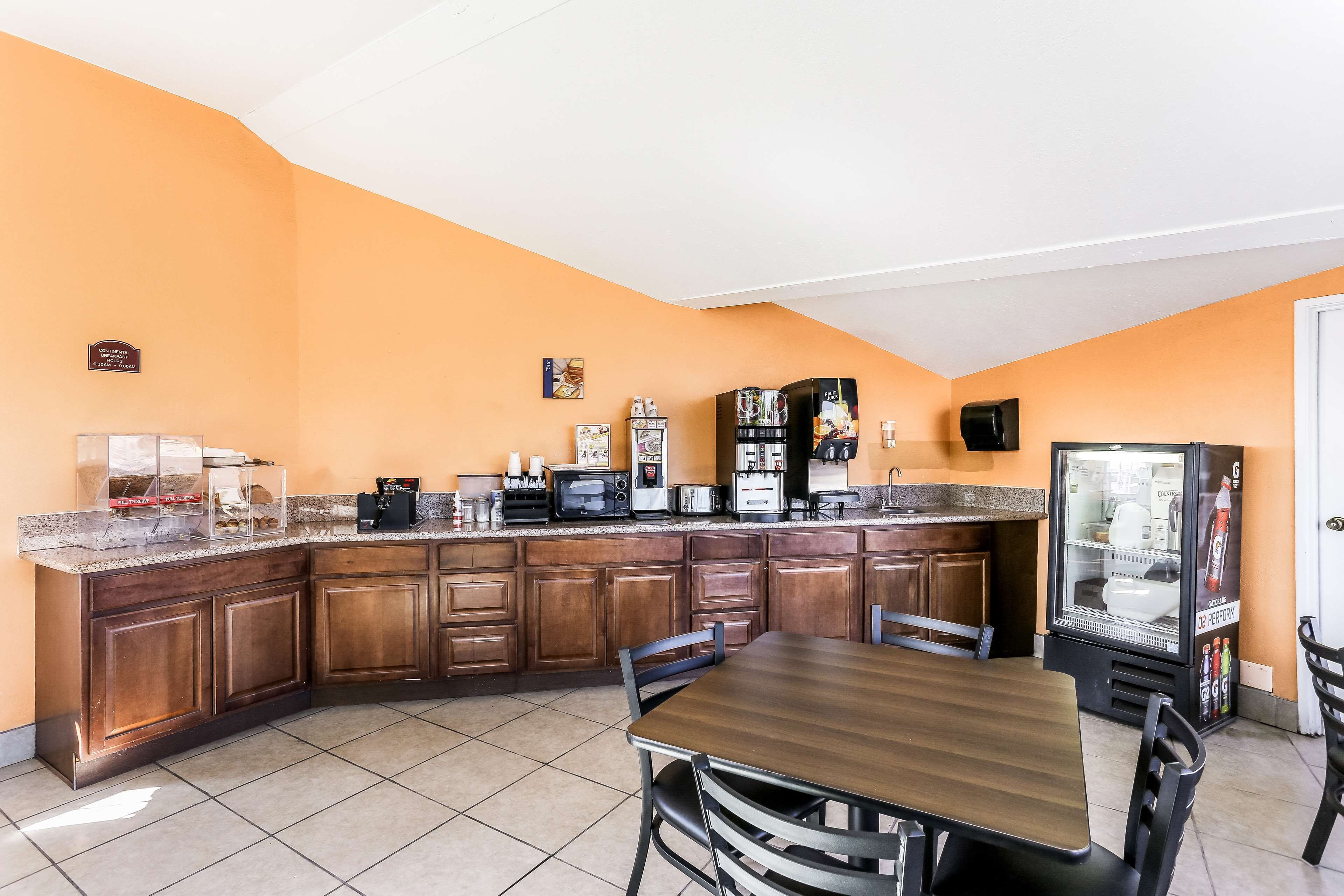 Cocina con armarios de madera, encimera de granito y refrigerador.
