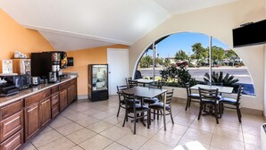 Um restaurante com cozinha, mesas de jantar e uma grande janela com vista para a rua.