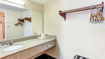 Un baño con lavamanos de encimera de granito, un espejo, toallero y barra para toallas.