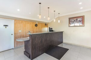 Una zona de recepción con un mostrador de madera oscura, un reloj y un cuadro en la pared.
