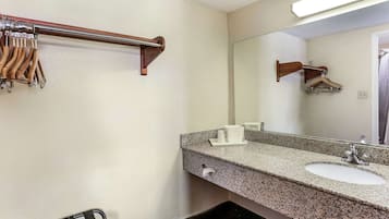 A bathroom with a granite countertop sink, a mirror, a towel rack, and a towel dispenser.