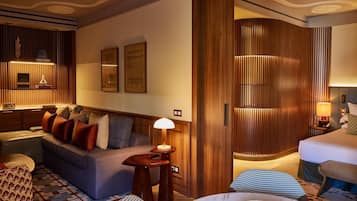 Une chambre d’hôtel avec un canapé, une petite table avec une lampe, un lit et un mur décoratif en bois.