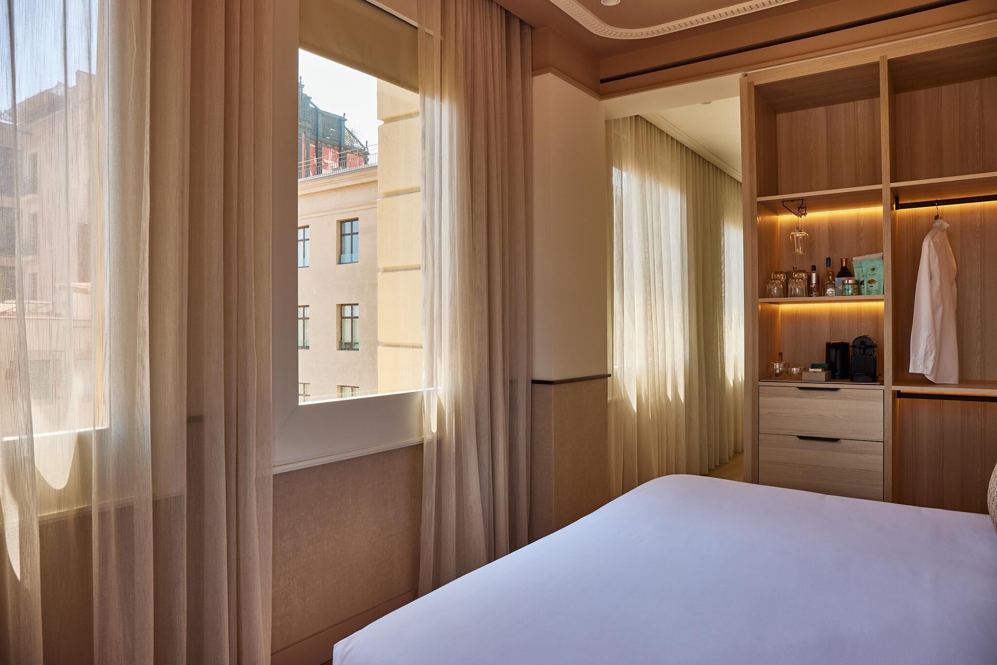 Habitación de hotel con una cama grande, un armario con espejo y una pequeña zona de estar con una mesa y sillas.