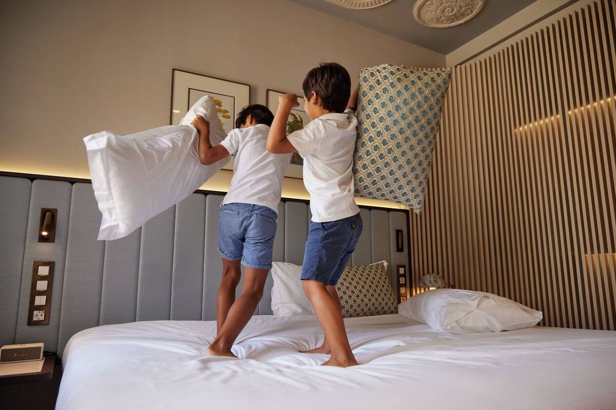 A hotel room with a bed, a nightstand, and a wall-mounted light fixture.