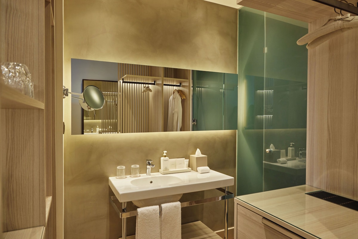 A modern bathroom with a large mirror, a sink, and a glass shower enclosure.