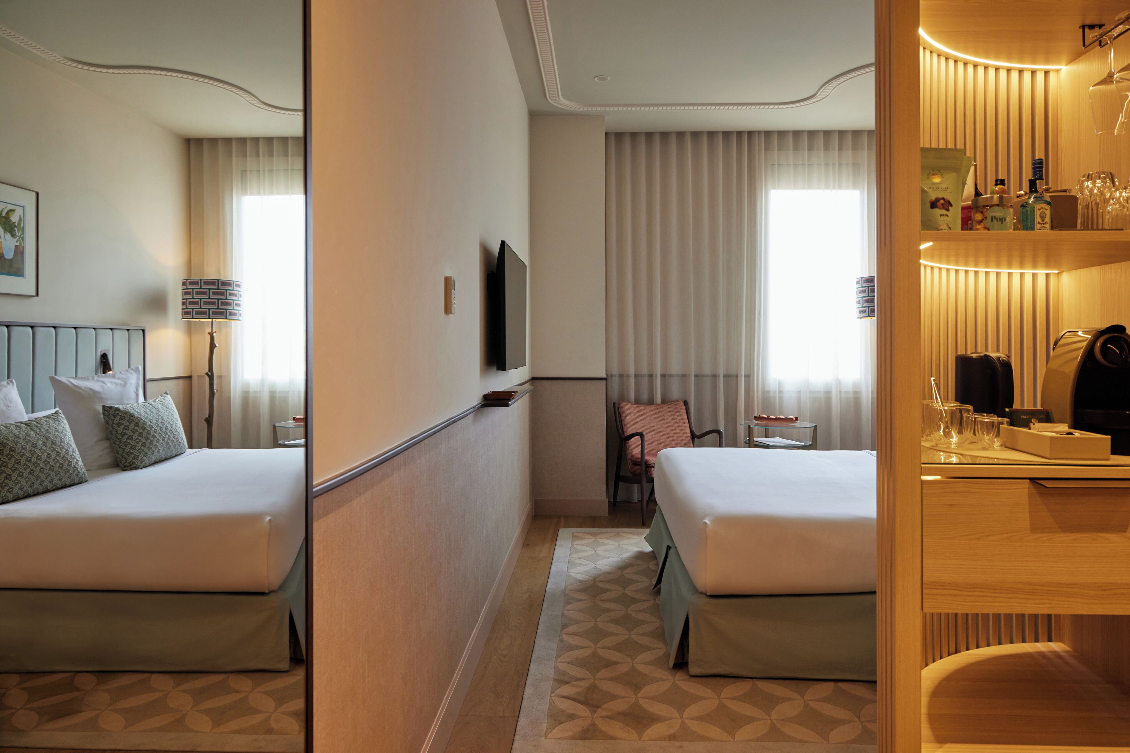 Habitación de hotel con una cama grande, televisión, escritorio con lámpara y ventana con cortinas.