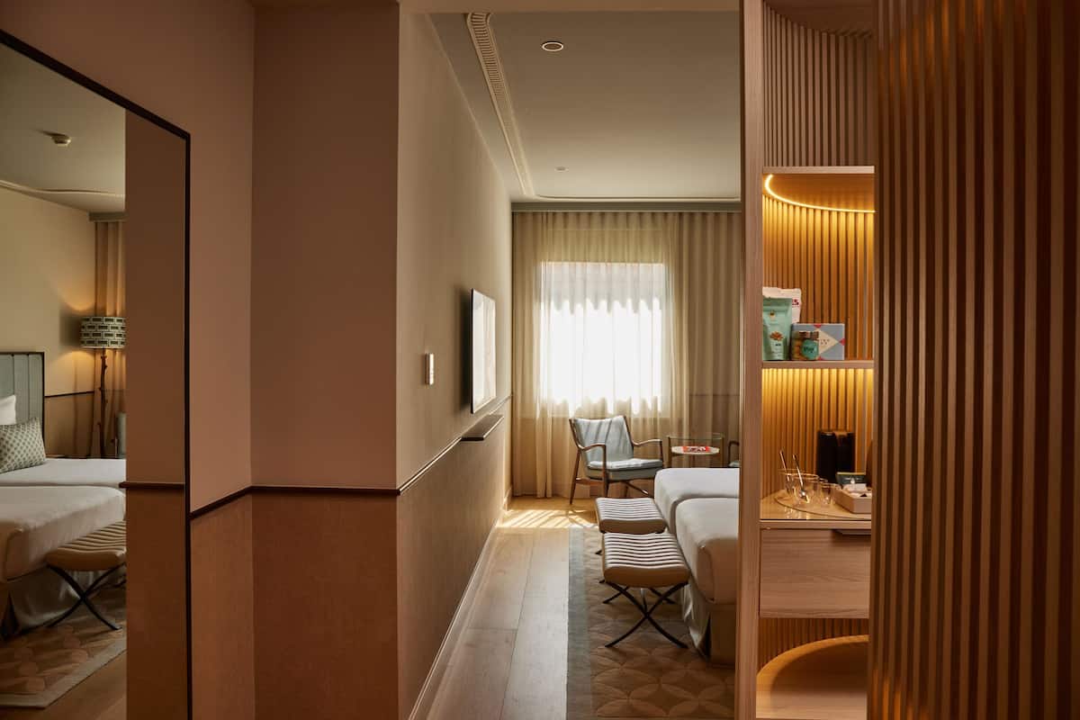 Une chambre d’hôtel avec un lit, un bureau, une chaise et un miroir.