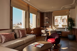 Una sala moderna con sofá, sillas, una mesa de centro y vistas a la ciudad.