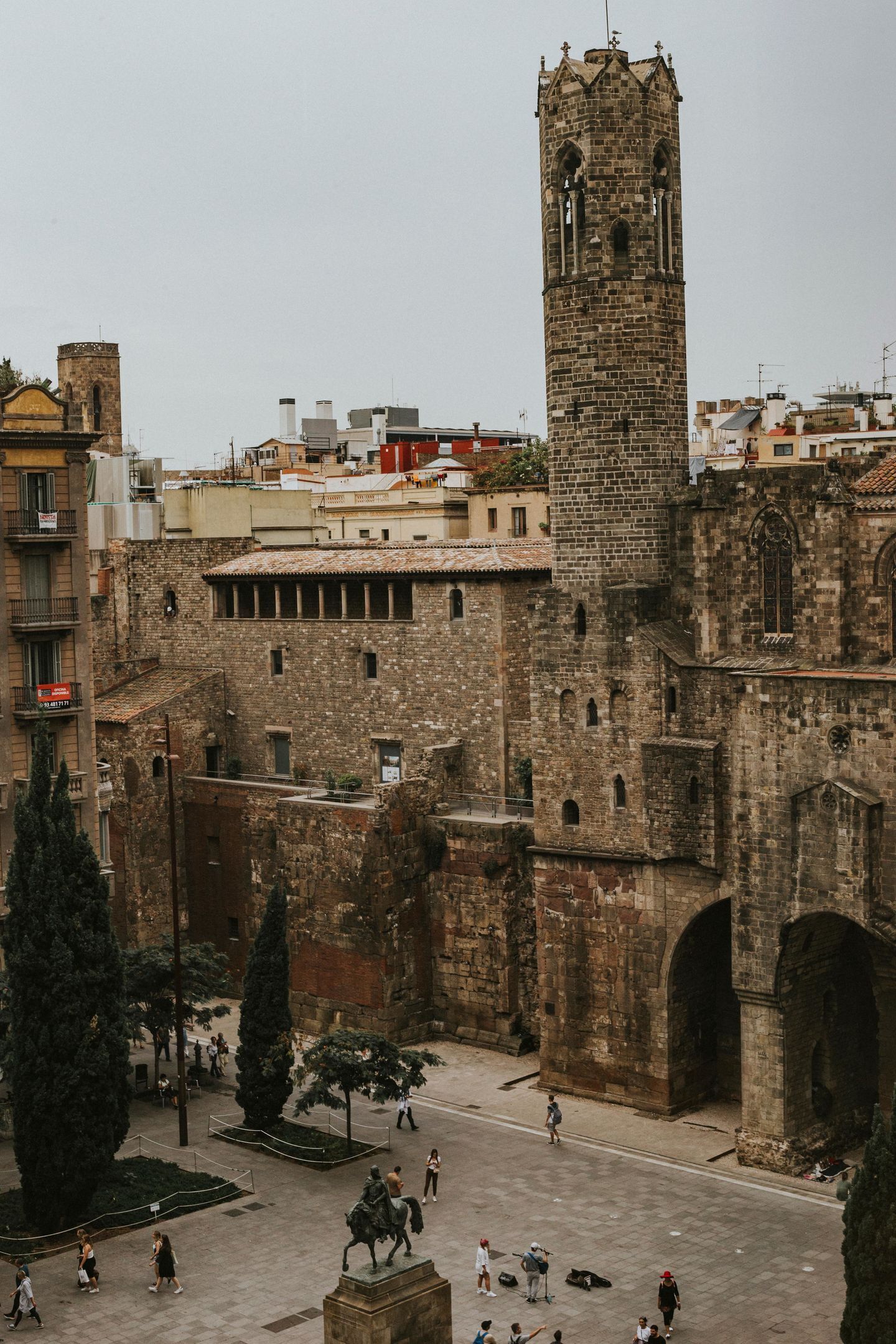 A historic stone building with a prominent tower and arched gateways.