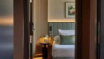 A hotel room with a bed, bedside table, lamp, and a framed picture on the wall.