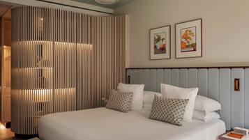 A hotel room with a large bed, a bedside table with a lamp, and two framed pictures on the wall.