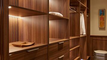 Un armario vestidor de madera con estantes y cajones múltiples, iluminado por luces debajo de los armarios.