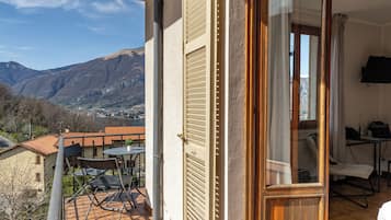 Un balcon avec vue sur les montagnes, une porte en bois et une table avec des chaises.