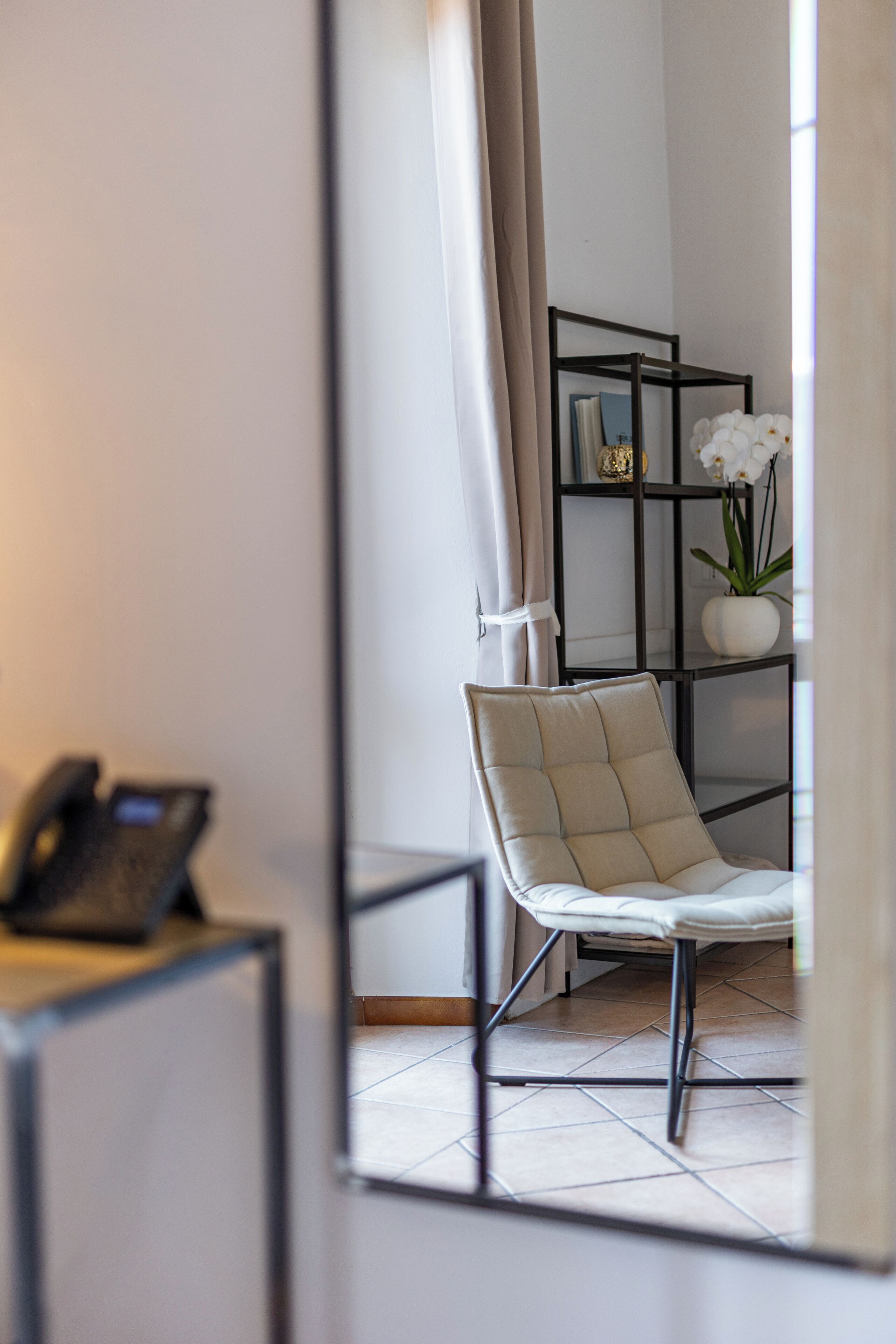 A modern room with a chair, a bookshelf, and a phone on a desk.