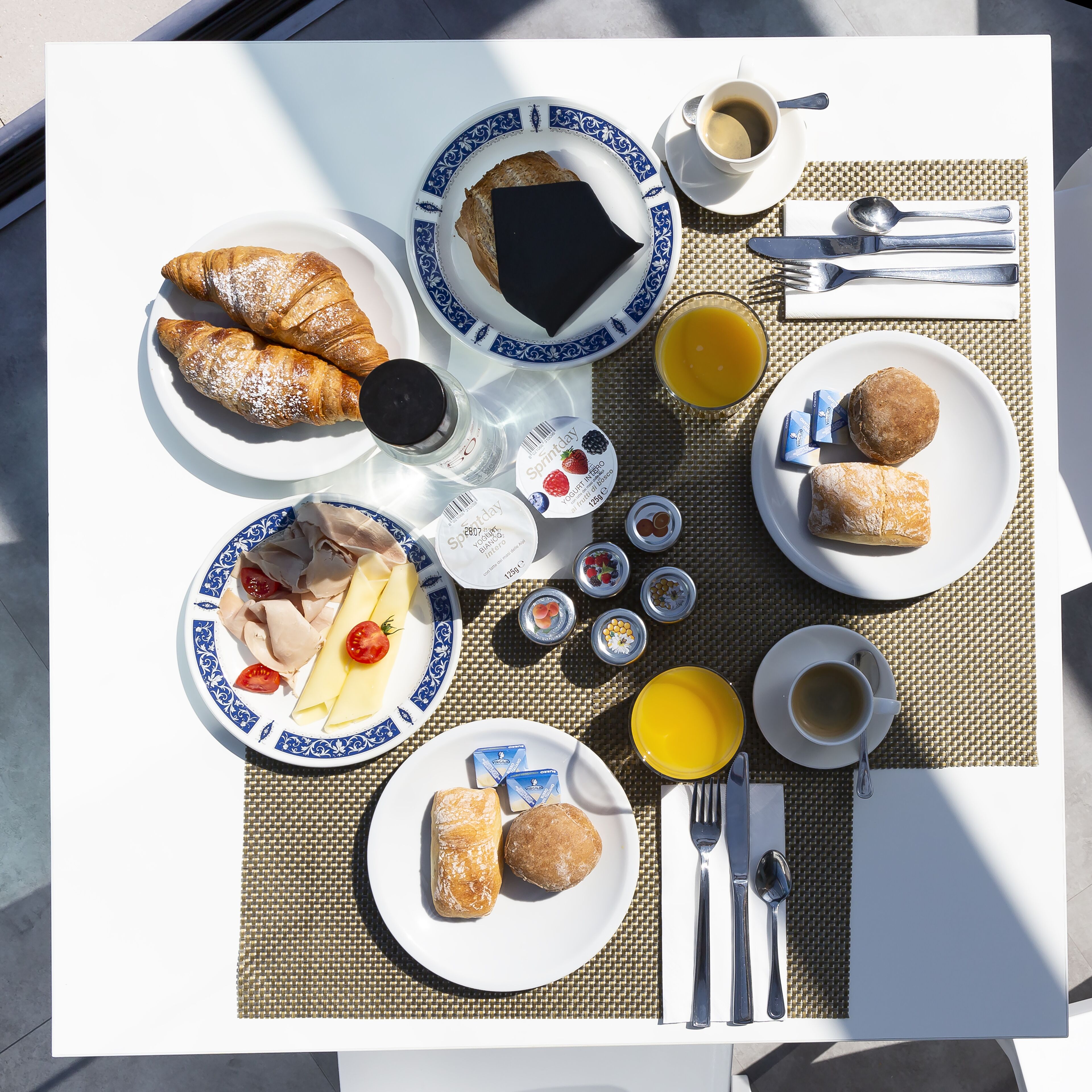 Une table de petit-déjeuner avec des croissants, du yaourt, des fruits et du café.