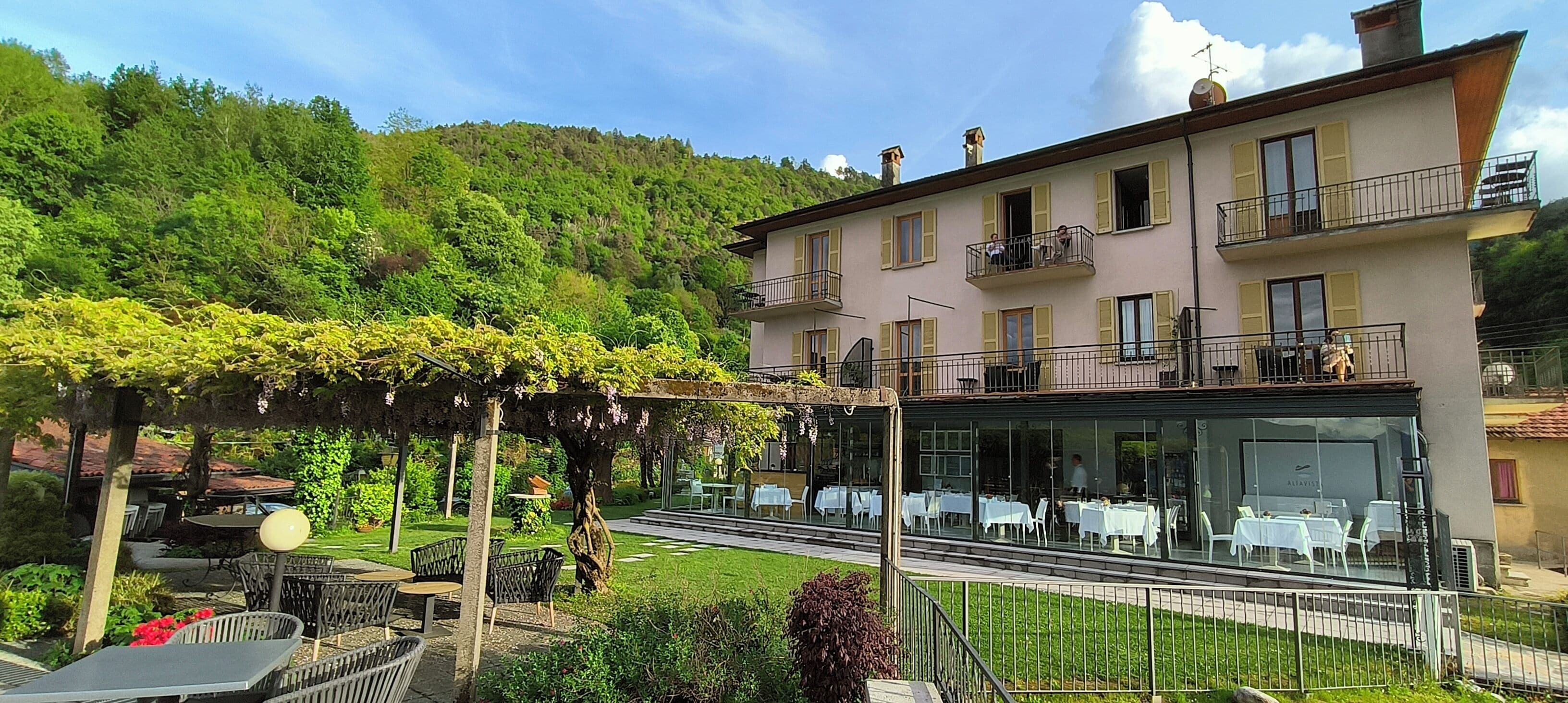 Un hotel con terraza exterior, fachada de vidrio y jardín.