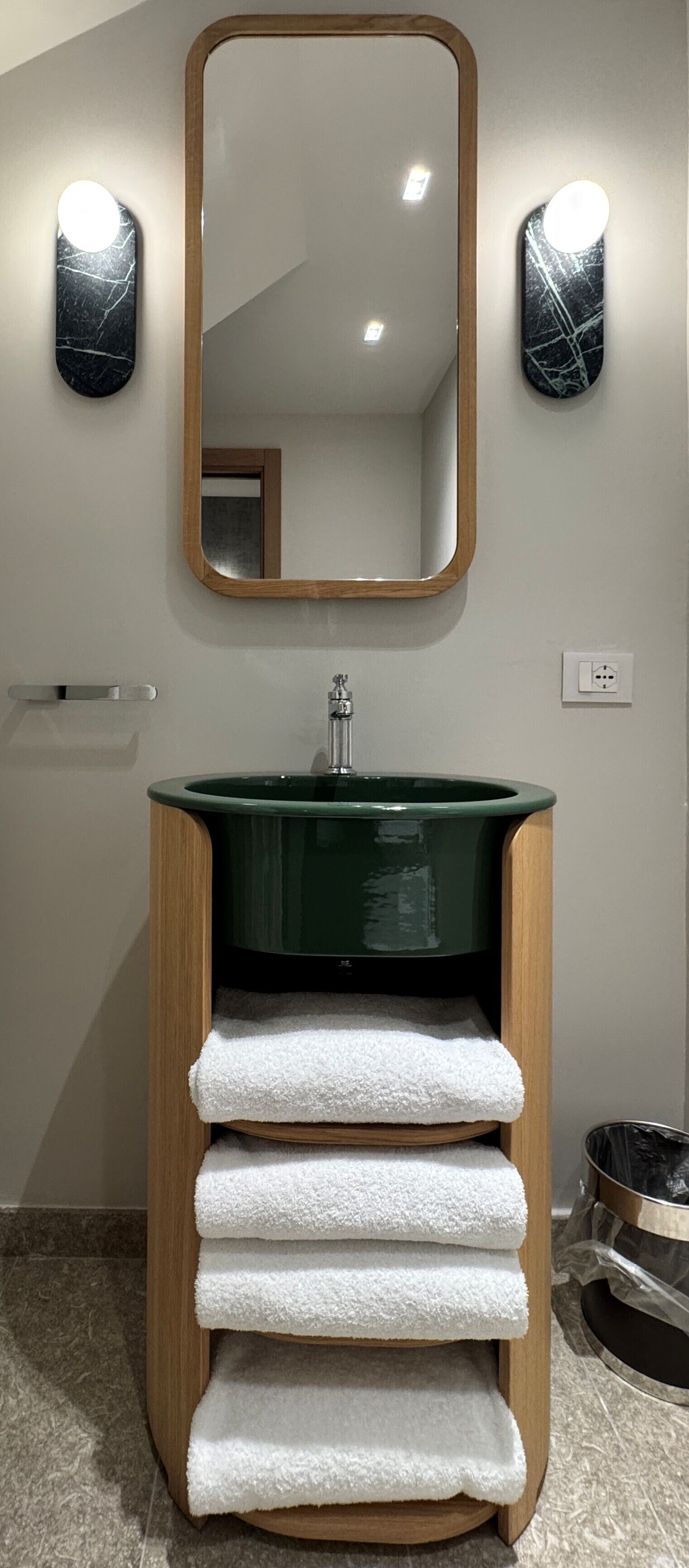 Un baño con un lavabo verde, un sujetabroques de madera y un espejo con iluminación.