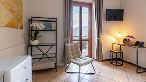 Una habitación moderna con sofá, televisión, escritorio con lámpara y vistas a las montañas.