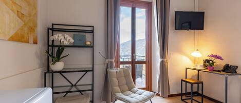 Een moderne kamer met een bank, een televisie, een bureau met lamp en uitzicht op de bergen.