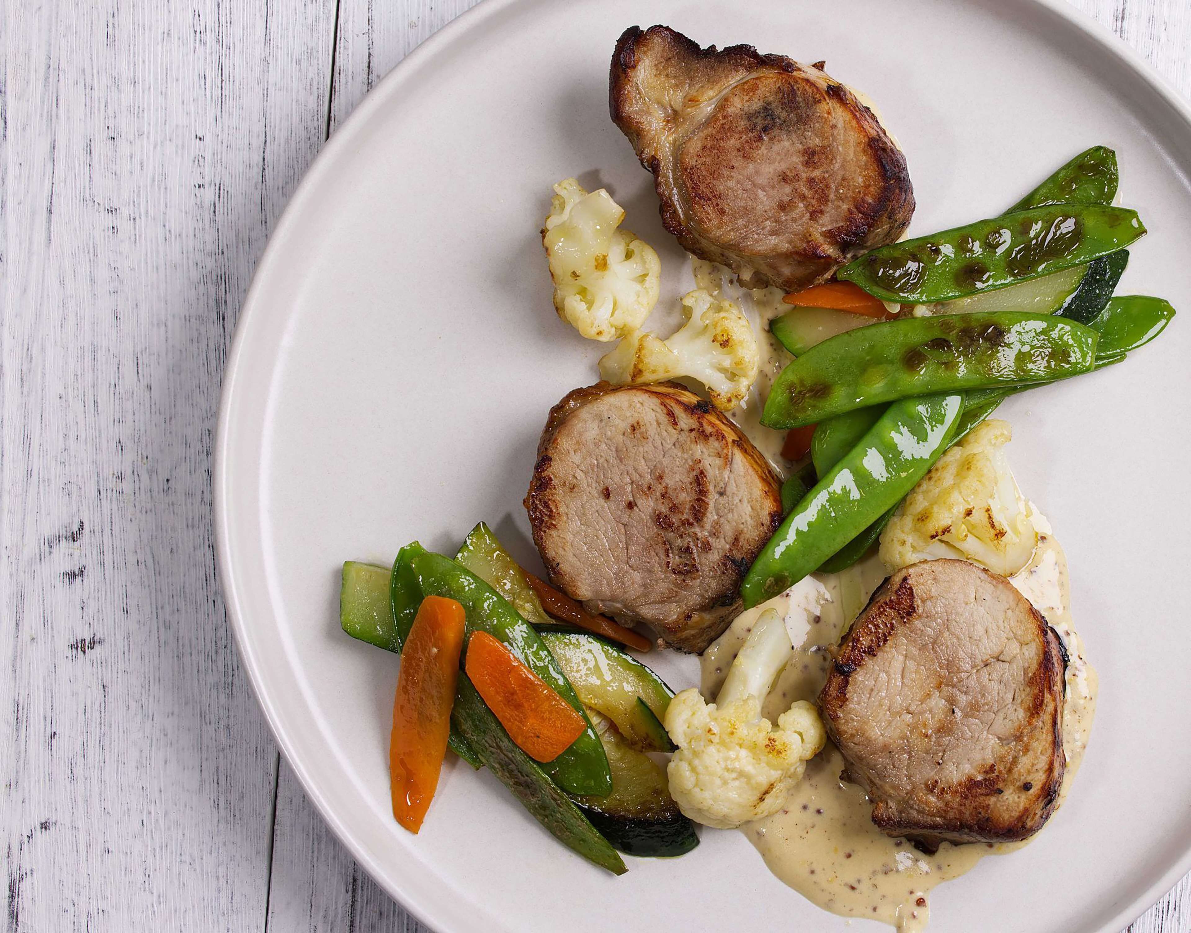 Une assiette de nourriture comprenant de la viande et des légumes grillés.