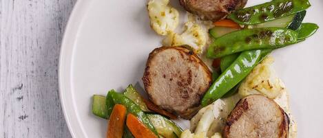 Une assiette de nourriture comprenant de la viande et des légumes grillés.