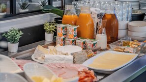 Un bufé con diversos alimentos, entre ellos queso, carnes y bebidas.