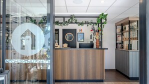 A reception desk with a modern design, a circular logo, and a plant display. - Campanile NATURE - Orange (Orange)