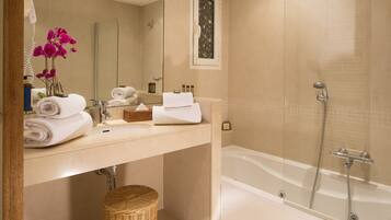 A bathroom with a bathtub, a sink, and a mirror. There are towels and a wicker basket.