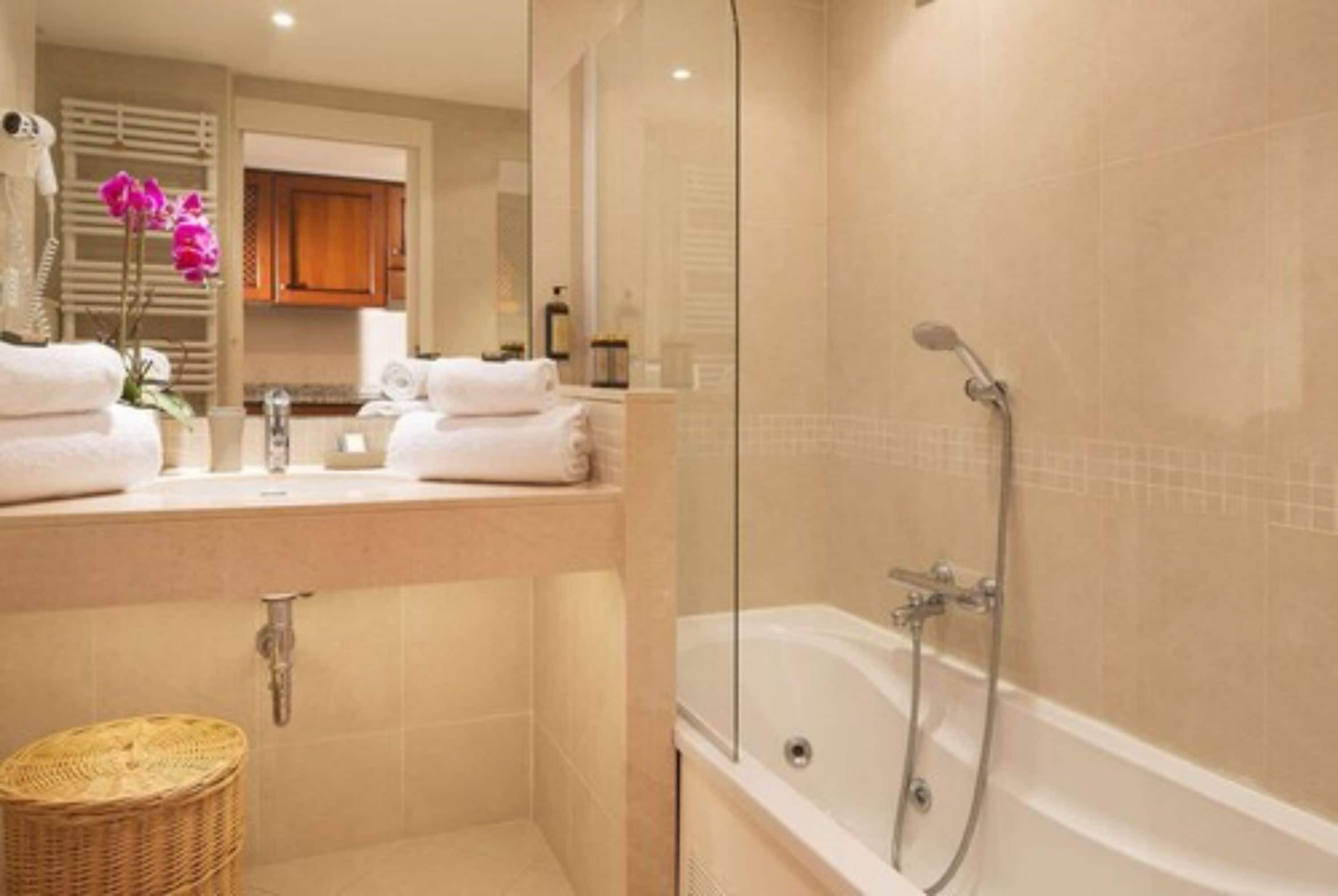 A modern bathroom with a glass-enclosed shower, a bathtub, and a vanity with a mirror.